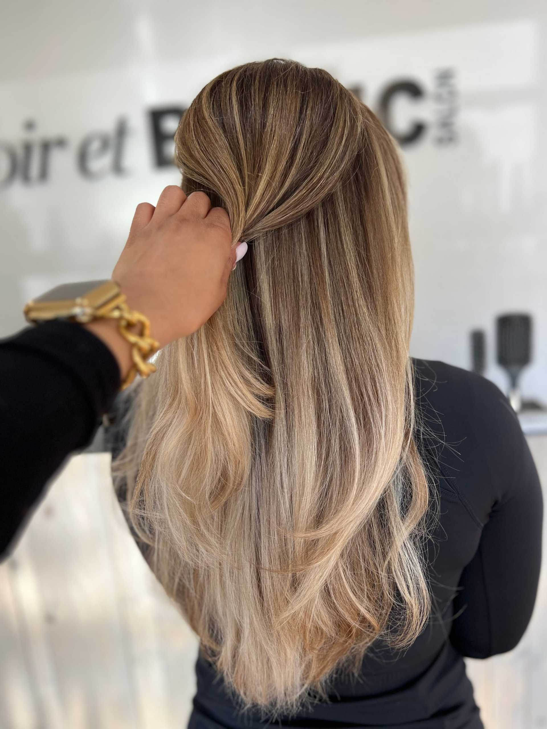 Woman with long, styled blonde hair in a salon setting.